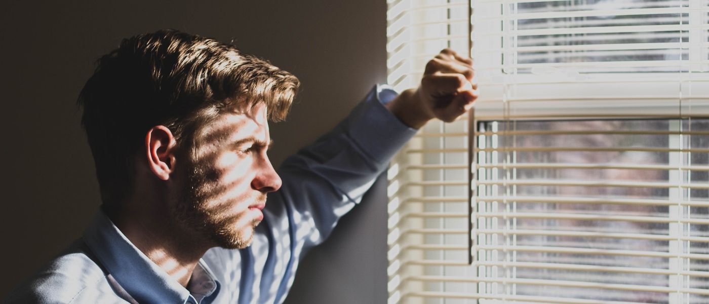 A man standing by a window, deep in thought